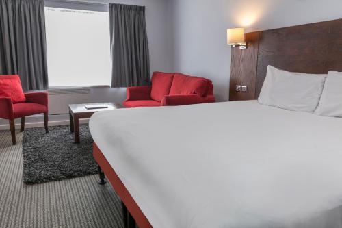 a hotel room with a bed and red chairs at The Stuart Hotel, Sure Hotel Collection by Best Western in Derby