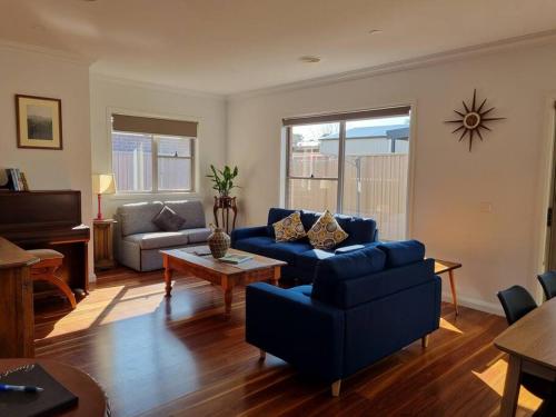 a living room with a blue couch and a table at 2 bedroom house Central Nagambie sleeps 5 in Nagambie
