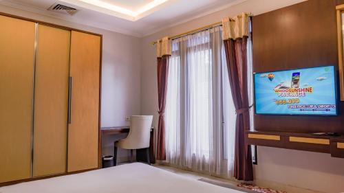 a room with a tv and a bed and a window at Grand Sunshine Resort & Convention in Bandung
