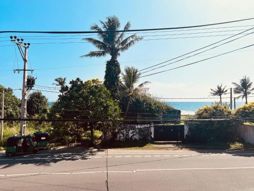 a palm tree on the side of a road with the ocean at Goviyapana Sky Breeze in Ahangama