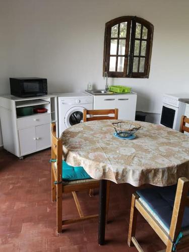 une cuisine avec une table et des chaises ainsi qu'une cuisine avec une cuisinière dans l'établissement La Tour dans haut de villa, à Porto-Vecchio