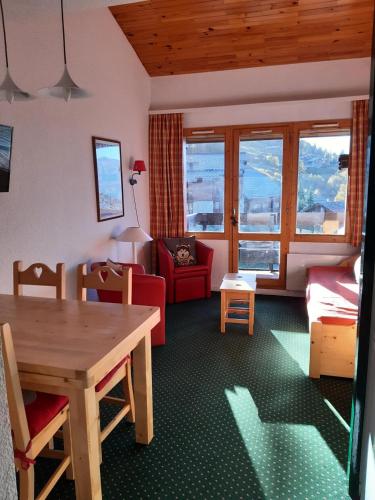 un salon avec une table et une chaise rouge dans l'établissement Résidence Le Hameau du Sauget - maeva Home - Appartement 2 pièces 6 personnes - Confort MAE-2334, à La Plagne Tarentaise