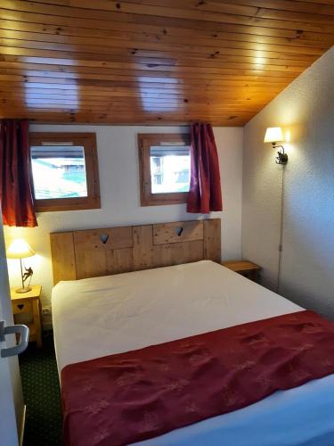 une chambre avec un grand lit avec deux fenêtres dans l'établissement Résidence Le Hameau du Sauget - maeva Home - Appartement 2 pièces 6 personnes - Confort MAE-2334, à La Plagne Tarentaise