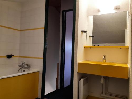 La salle de bains est pourvue d'un lavabo jaune et d'un miroir. dans l'établissement Résidence Le Hameau du Sauget - maeva Home - Appartement 2 pièces 6 personnes - Confort MAE-2334, à La Plagne Tarentaise