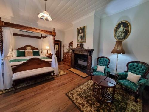 une chambre avec un lit et deux chaises et une cheminée dans l'établissement Storekeepers Cottage Guesthouse, à Stroud