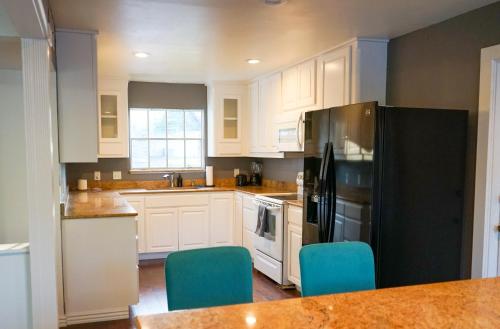 a kitchen with white cabinets and a black refrigerator at Artsy Bohemian - 2 Min to Airport -TheGoodPlace#2 in San Antonio