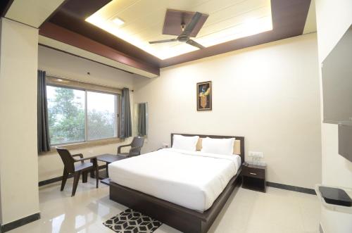 ナスドワーラにあるHotel shree Dhwaja Inn - 100 meter from shreenathji Templeのベッドとテーブルと椅子のある寝室
