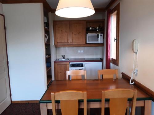 une cuisine avec une table, des chaises et un téléphone dans l'établissement Résidence La Marelle et Le Rami - maeva Home - Appartement 2 pièces 5 personnes - Sélection MAE-6804, à La Plagne Tarentaise