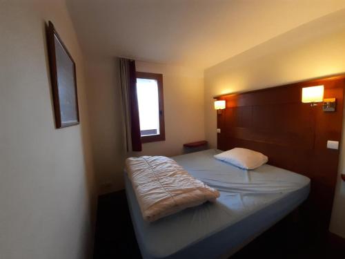 une chambre avec un lit avec une tête de lit en bois dans l'établissement Résidence La Marelle et Le Rami - maeva Home - Appartement 2 pièces 5 personnes - Sélection MAE-6804, à La Plagne Tarentaise