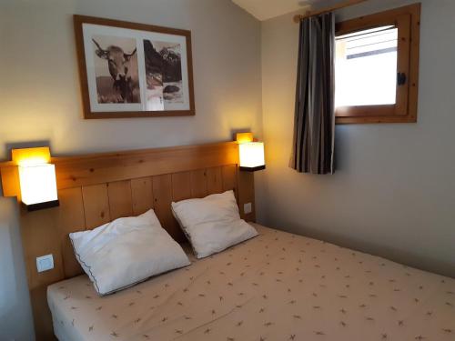 - une chambre avec un lit avec deux oreillers et une fenêtre dans l'établissement Résidence La Marelle et Le Rami - maeva Home - Appartement 3 pièces 7 personnes - Sélection MAE-8654, à La Plagne Tarentaise