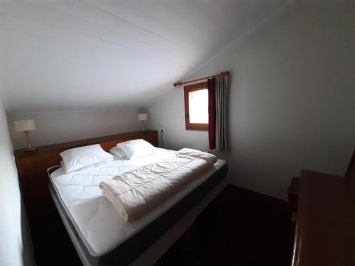 une chambre avec un lit avec des draps blancs et une fenêtre dans l'établissement Résidence La Marelle et Le Rami - maeva Home - Appartement 3 pièces 7 personnes - Sélection MAE-8774, à La Plagne Tarentaise