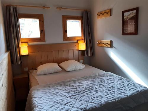 - une chambre avec un lit avec deux oreillers et deux fenêtres dans l'établissement Résidence La Marelle et Le Rami - maeva Home - Appartement 2 pièces 5 personnes - Sélection MAE-4514, à La Plagne Tarentaise
