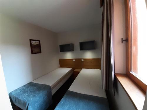 une petite chambre avec deux lits et une fenêtre dans l'établissement Résidence La Marelle et Le Rami - maeva Home - Appartement 2 pièces 4 personnes - Sélection MAE-0924, à La Plagne Tarentaise
