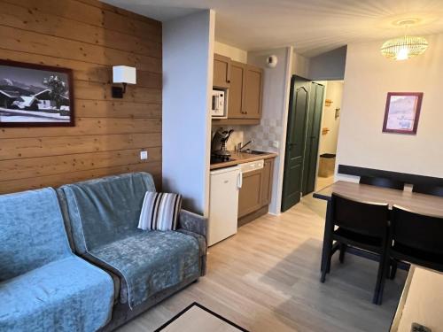 un salon avec un canapé bleu et une cuisine dans l'établissement Résidence La Marelle et Le Rami - maeva Home - Appartement 2 pièces 4 personnes - Sélection MAE-5721, à La Plagne Tarentaise