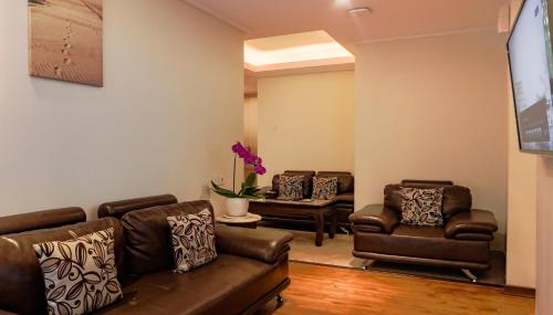 a living room with leather couches and chairs at Grand Sunshine Resort & Convention in Bandung