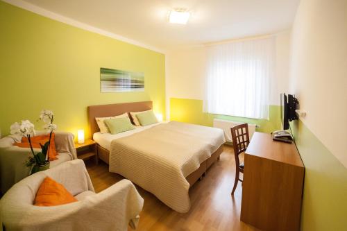 a bedroom with two beds and a chair and a table at Hotel am Gutspark in Leipzig