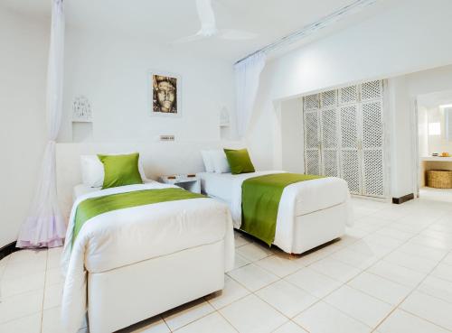 two beds in a white room with green and white sheets at Casa Zuri Diani Beach Villa in Diani Beach
