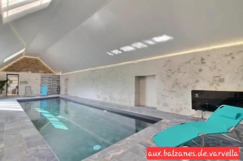 - une piscine avec des chaises bleues dans la chambre dans l'établissement Aux balzanes de Varvella Piscine intérieure privée chauffée, à Ploudaniel