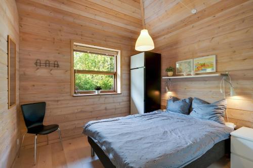 a bedroom with wooden walls and a bed and a chair at Beautiful And Family-Friendly Holiday Home For 9 People With A Spa Bath Near Grenaa Beach in Grenå