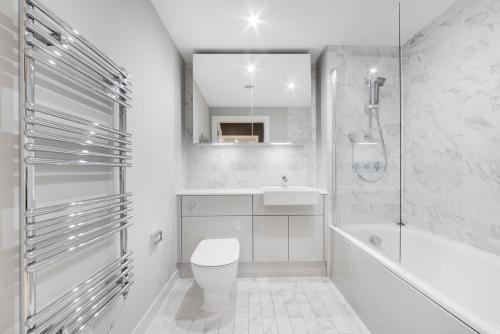 a white bathroom with a toilet and a tub and a sink at Modern 2 Bed Heart of Elephant Castle in London