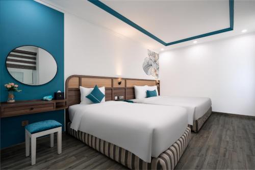 two beds in a room with blue walls and a mirror at Paracel Beach Hotel in Da Nang