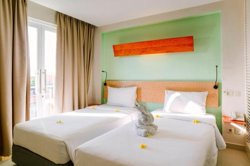 two beds in a room with green walls at HARRIS Hotel & Residences Riverview Kuta, Bali in Kuta