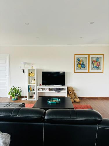 a living room with a black couch and a tv at Family home in Mount Colah