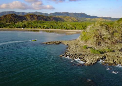 a boat in the water next to a beach at Los Vivos Beachfront Experience in Pochote