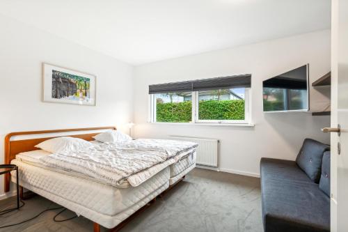 a bedroom with a bed and a couch and two windows at Beautiful Ground-Floor Holiday Apartment With A Sea View in Ebeltoft