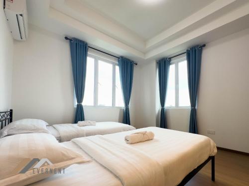 two beds in a bedroom with blue curtains at Serene Heights by Evernent in Miri