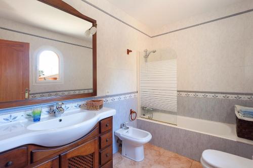 a bathroom with a sink and a toilet and a mirror at Villa Almirante in Badia Gran