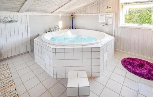 a bathroom with a large tub with a purple rug at Holiday Home Otterup With Sauna 302 in Otterup
