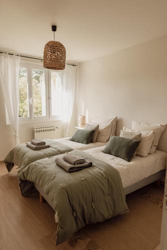 une chambre blanche avec deux lits avec des serviettes dessus dans l'établissement GITE LE TILLEUL, à Mormoiron