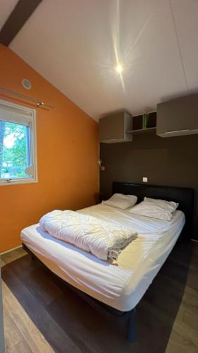 - un grand lit dans une chambre dotée d'un mur orange dans l'établissement Mobil-home 316 3 chambres domaine de la forge 4 étoiles bassin arcachon, à La Teste-de-Buch