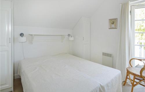 a white bedroom with a bed and a chair at Søhøjlandet in Gjern