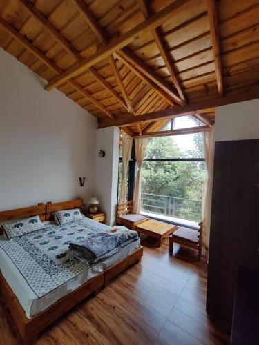 a bedroom with a bed and a large window at Oakakhi Stays, Deluxe room in Rānīkhet