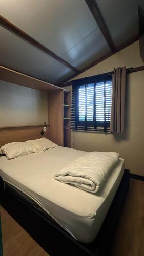 un grand lit dans une chambre avec une fenêtre dans l'établissement chalet 315 camping 4 étoiles Bassin d'Arcachon La Teste, à La Teste-de-Buch