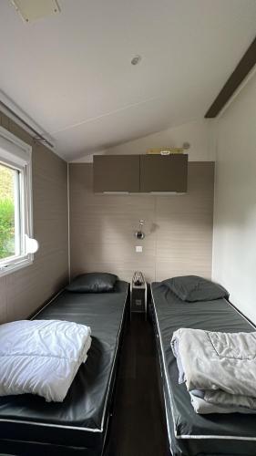 - 2 lits dans une petite chambre dans l'établissement Mobil Home 220 aménagé 2 chambres la teste camping 4 etoiles, à La Teste-de-Buch