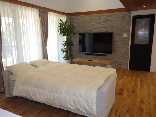 a large white bed in a room with a television at Villax富山 in Tonami