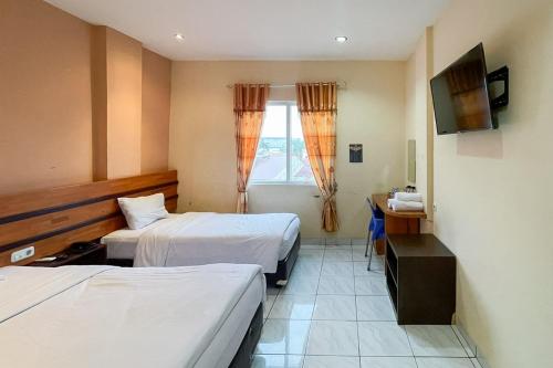 a hotel room with two beds and a television at RedDoorz at Hotel Anda Pematang Siantar in Pematangsiantar