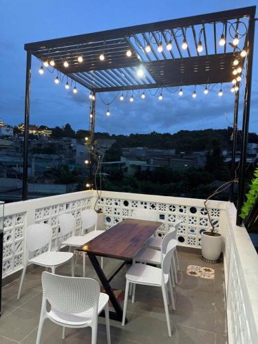 a wooden table and chairs on a balcony with lights at Sea-Breeze Homestay in Phan Thiet