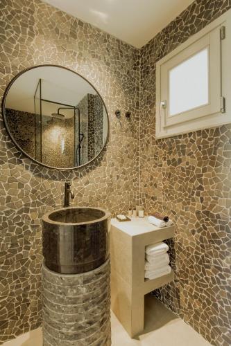 a bathroom with a round mirror and a sink at Opal Paros in Naousa