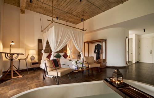 a living room with a bath tub and a bedroom at aNhill Boutique in Hue