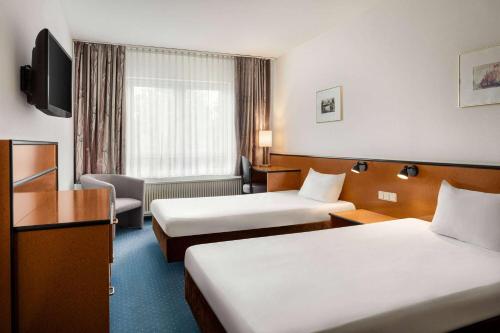 a hotel room with two beds and a television at Aspire Frankfurt Airport, Trademark Collection by Wyndham in Rüsselsheim