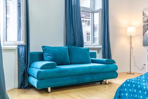 a blue couch in a living room with windows at Elegant 2BR Apt.@Wiener Stadthalle/Central Located in Vienna