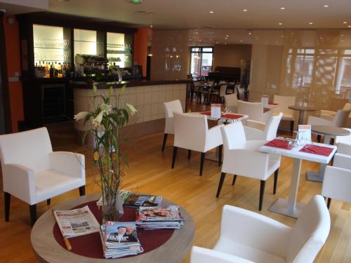 a restaurant with white chairs and tables and a bar at La Résidence Therm’Appart in Vichy