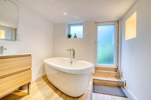 une baignoire blanche dans une salle de bain avec fenêtres dans l'établissement La Grande Cordée - Appt au pied des Pyrénées, à Ax-les-Thermes