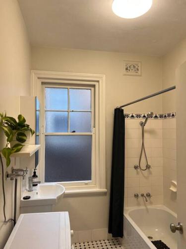 a bathroom with a window and a tub and a sink at Golden Dream in Sydney