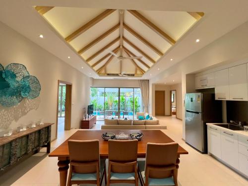 a kitchen and living room with a table and chairs at Trichada Villas by RESAVA in Bang Tao Beach