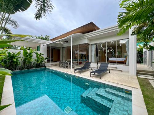 a swimming pool in front of a house at Trichada Villas by RESAVA in Bang Tao Beach